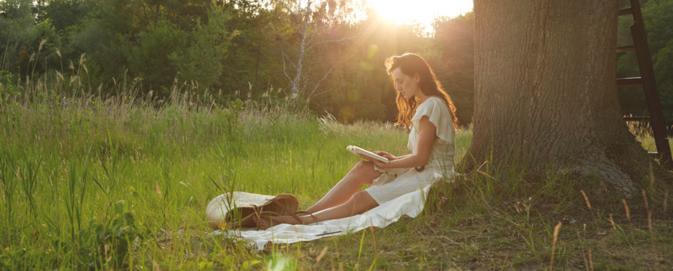 Mujer bajo un arbol leyendo un libro