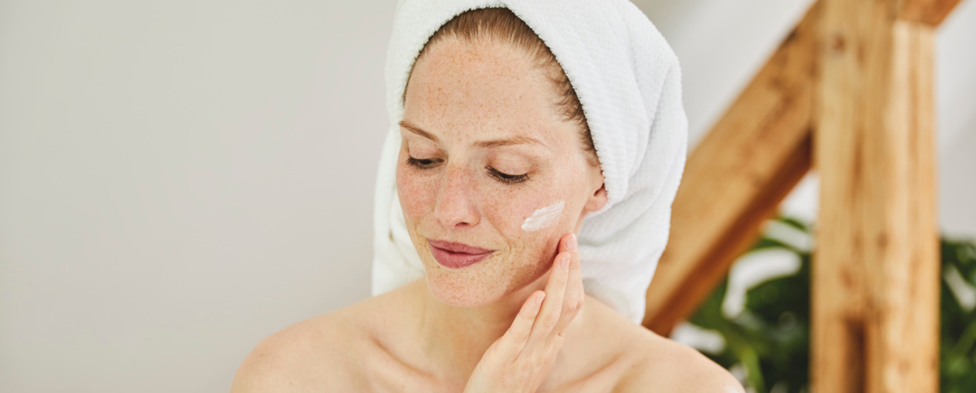 Mujer aplic&aacute;ndose crema hidratante en la cara
