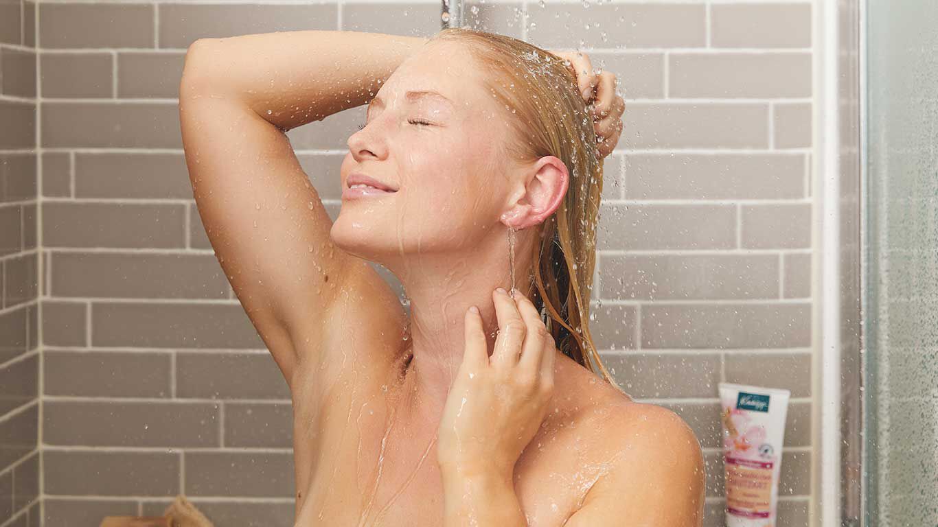 Une femme blonde est sous la douche.