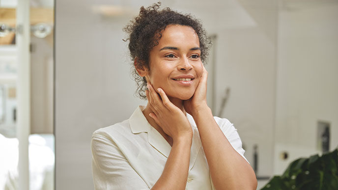 Une femme regarde son visage dans le miroir