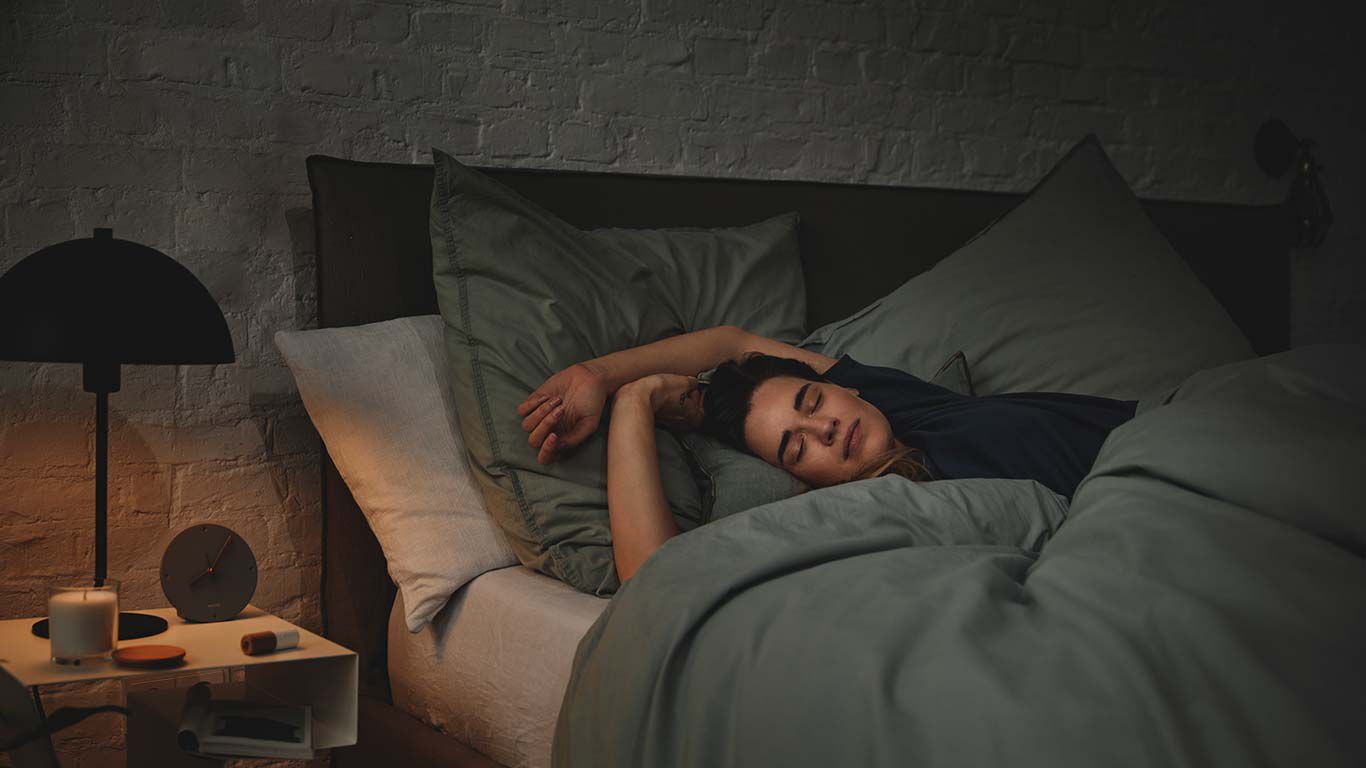 Une femme est couchée dans son lit et dort.