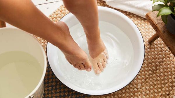 Les pieds dans un sage seau d'eau froide. À gauche, un deuxième seau rempli d'eau chaude.