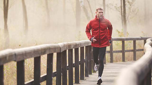 クナイプコラムの動き自然の中で木製の橋をジョギングで渡る男性。