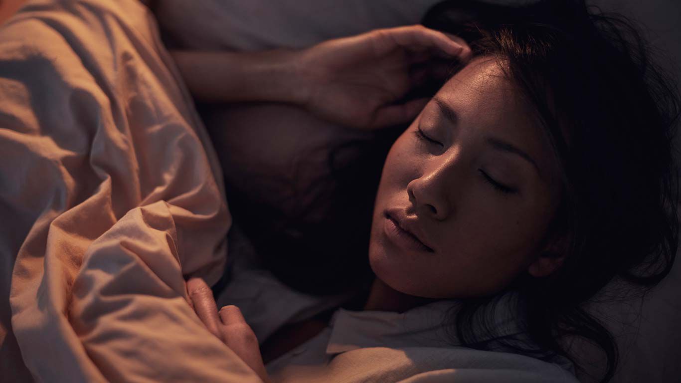 暗い寝室：ベッドに横たわる女性。
