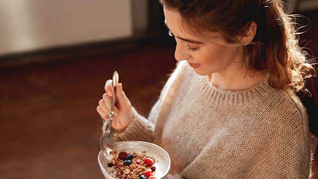 ベリーとミューズリーを食べる女性。