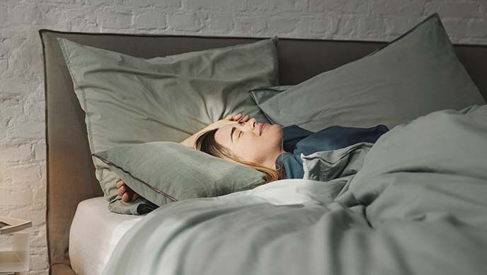 ベッドに横になって寝ている女性。